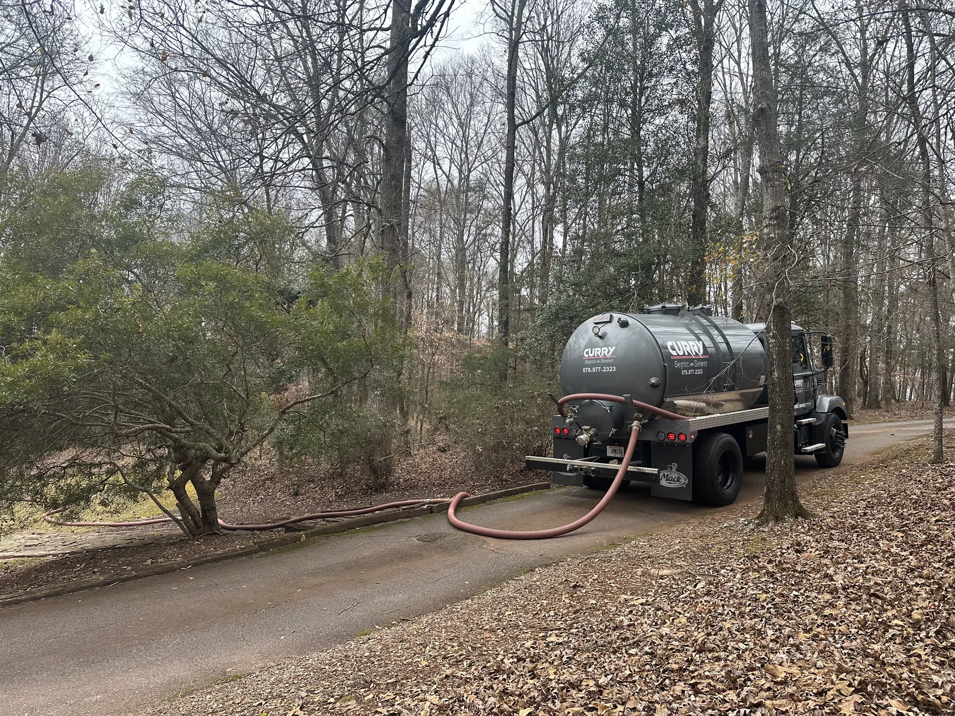 Curry septic pump truck wooded driveway
