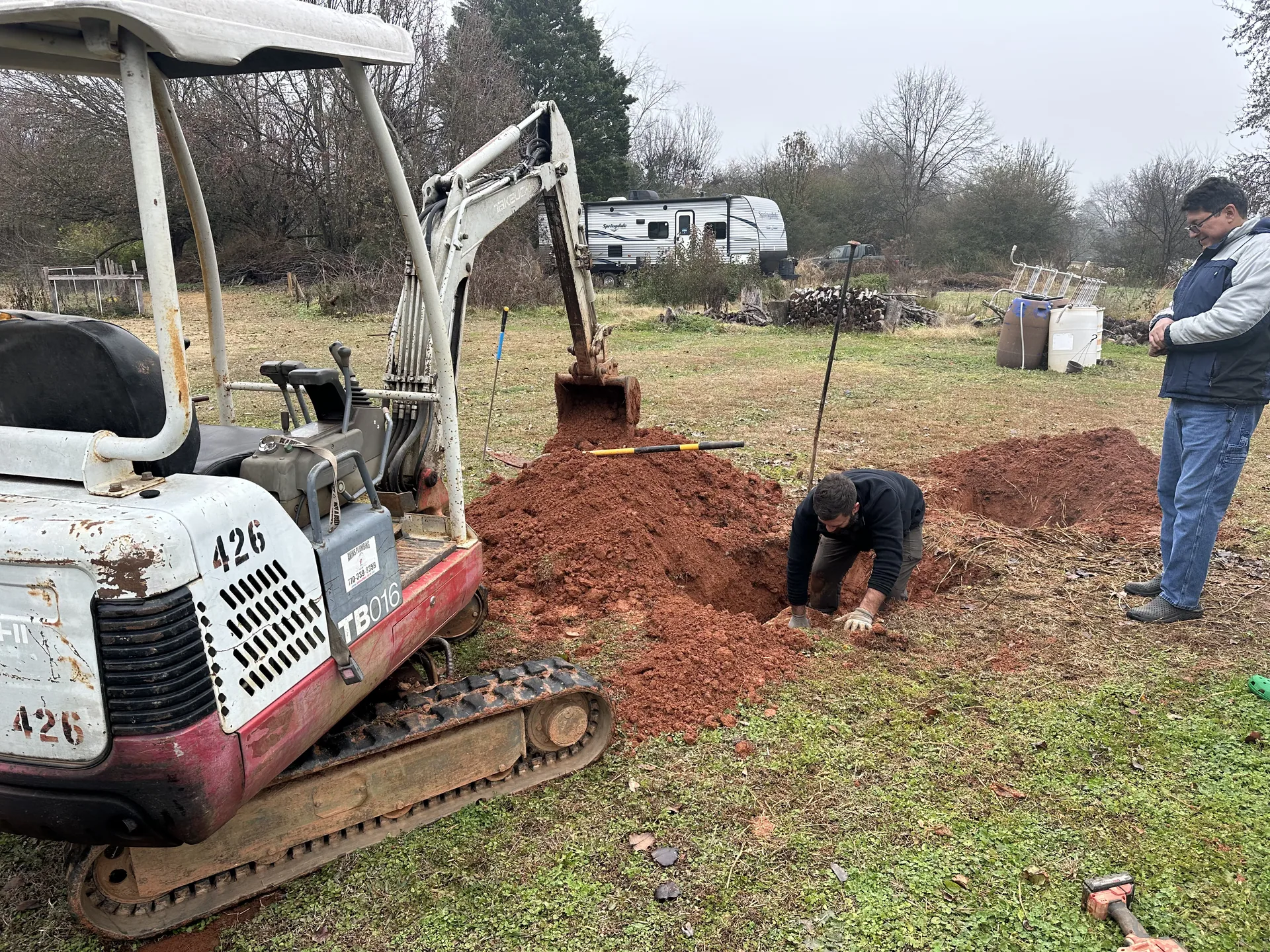 Mini excavator septic trench digging crew