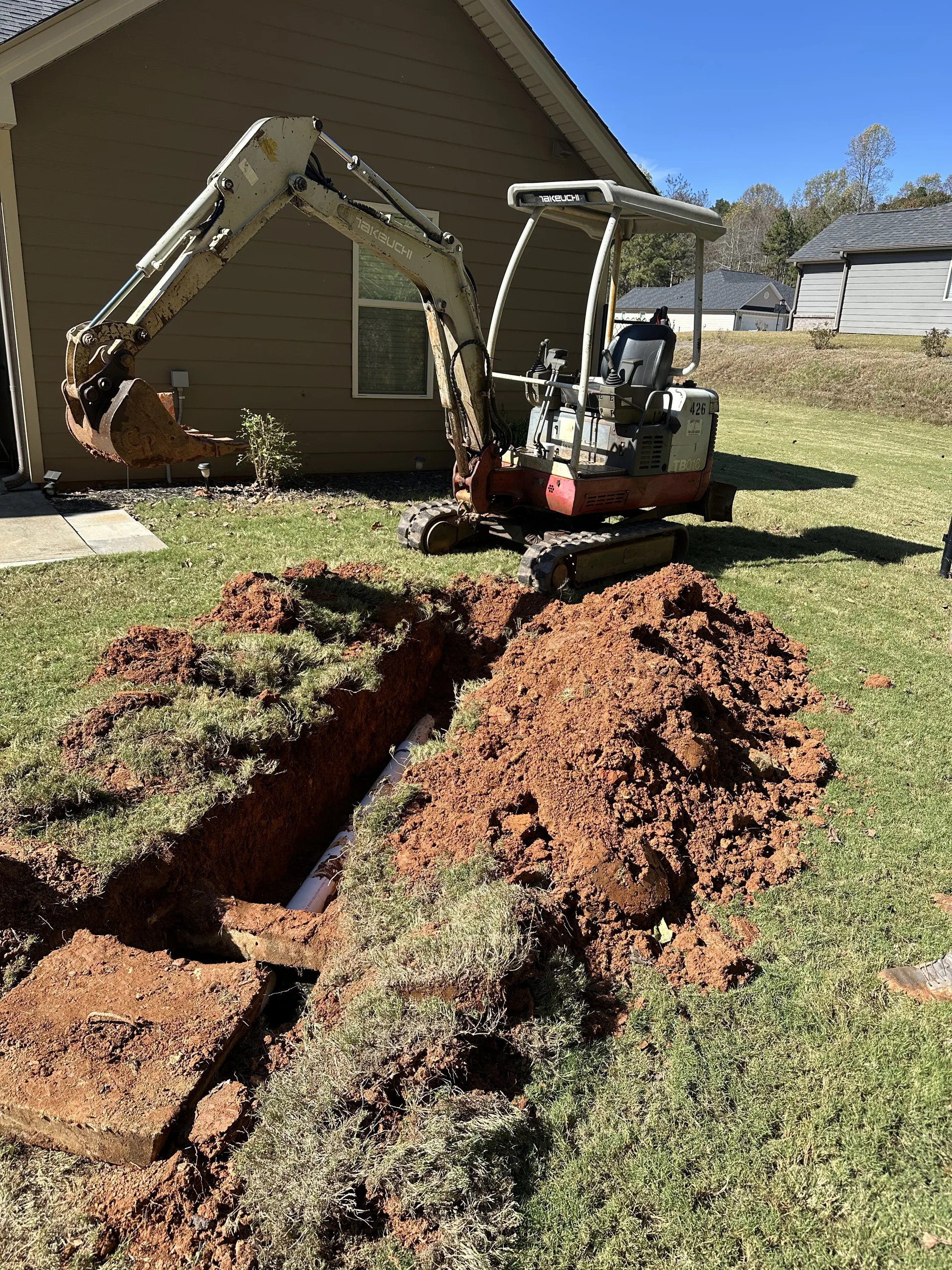 Mini excavator trench digging residential yard